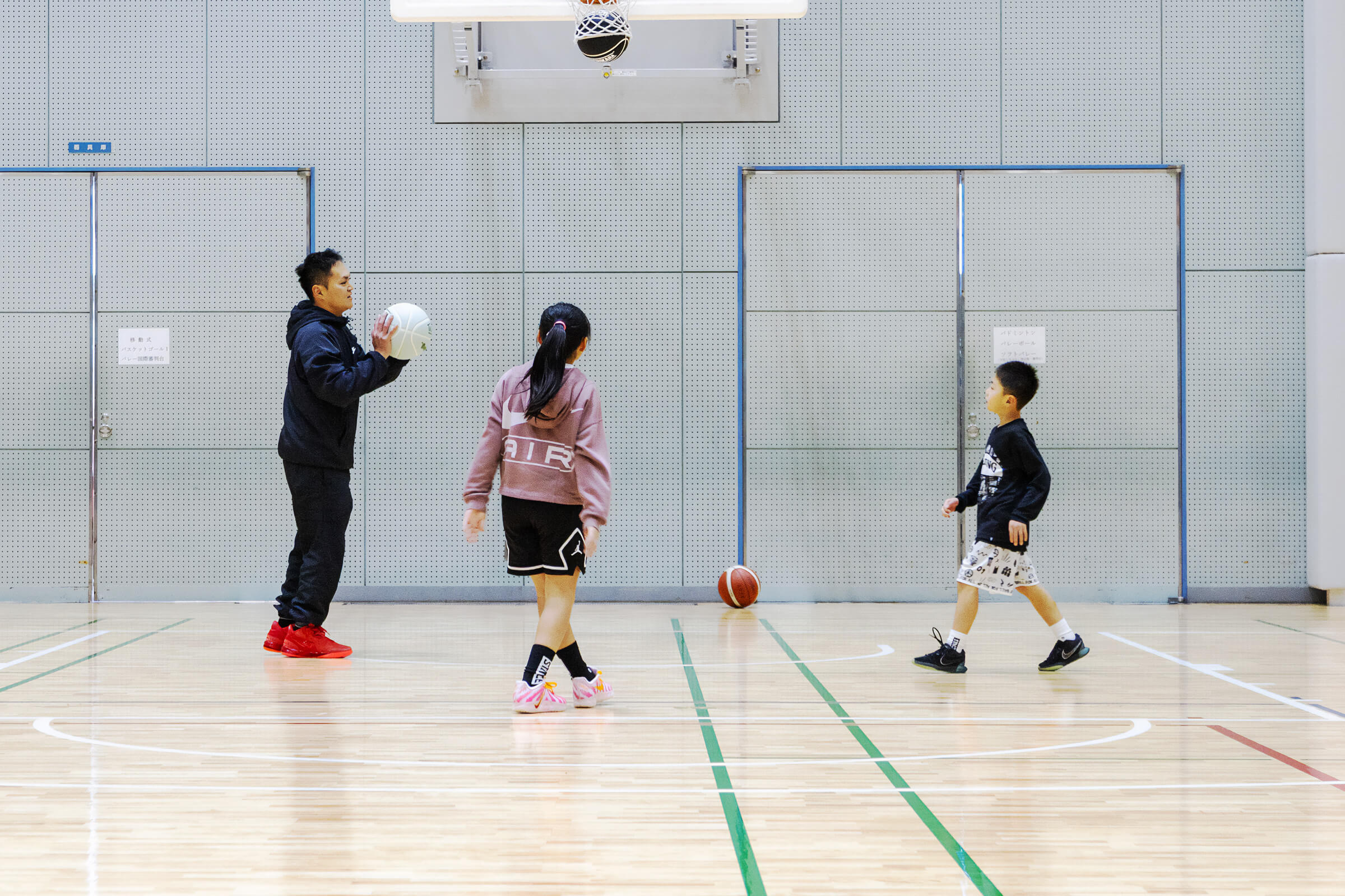 三豊市総合体育館アリーナでバスケットボールを楽しむ家族。父親と女の子、男の子